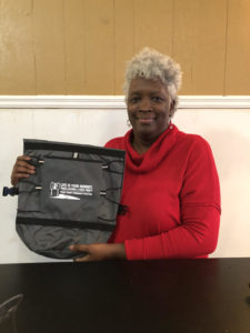 Perry County stakeholder and Board of Education liaison, Verlander Jones shows a duffle bag as she assists Coordinator Robertson identify, label,  divide and deliver promotional items for the counselors and Peer Helper lead teachers at Francis Marion High School in Marion, AL and Robert C. Hatch in Uniontown, AL